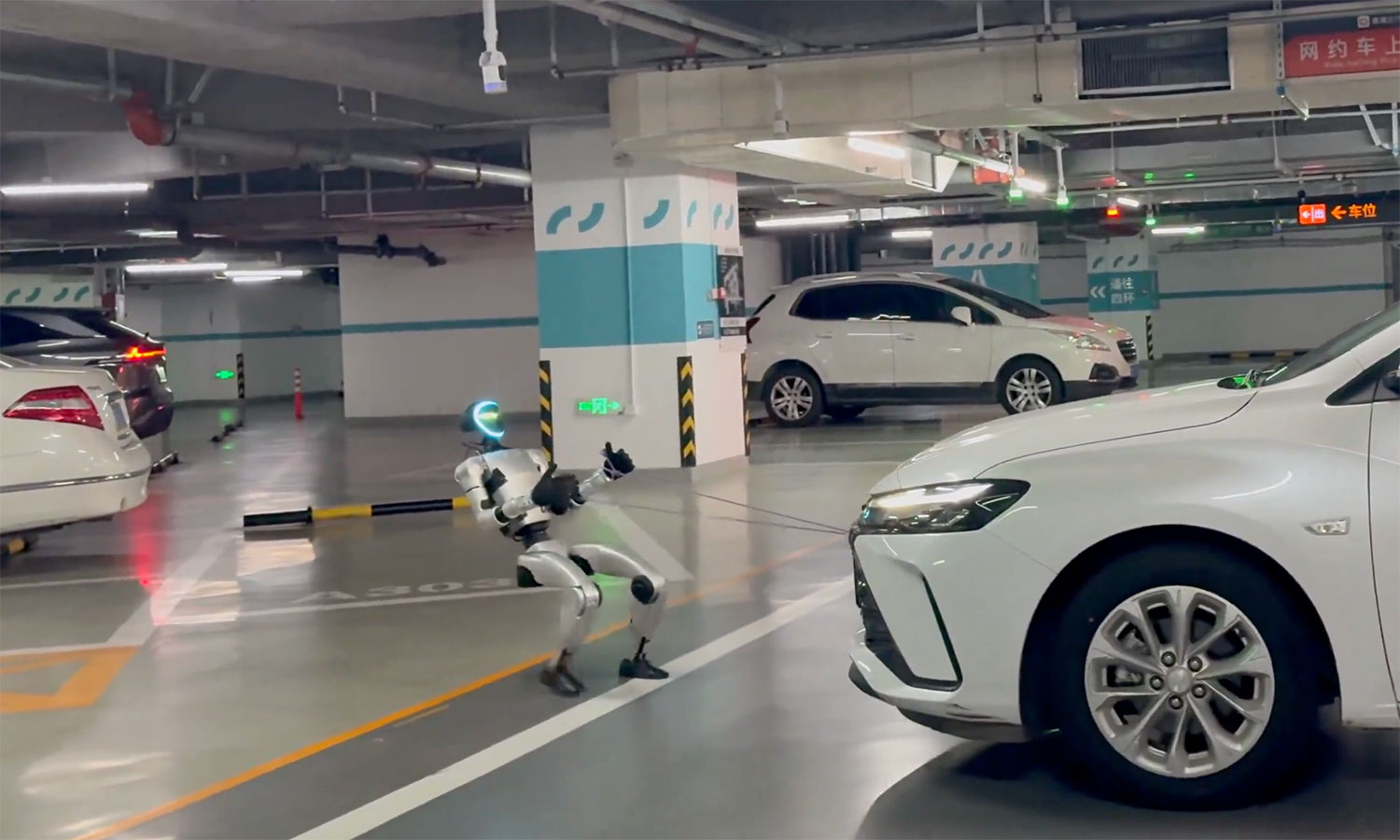 Mały humanoidalny robot holuje samochód. I robi to naprawdę dobrze